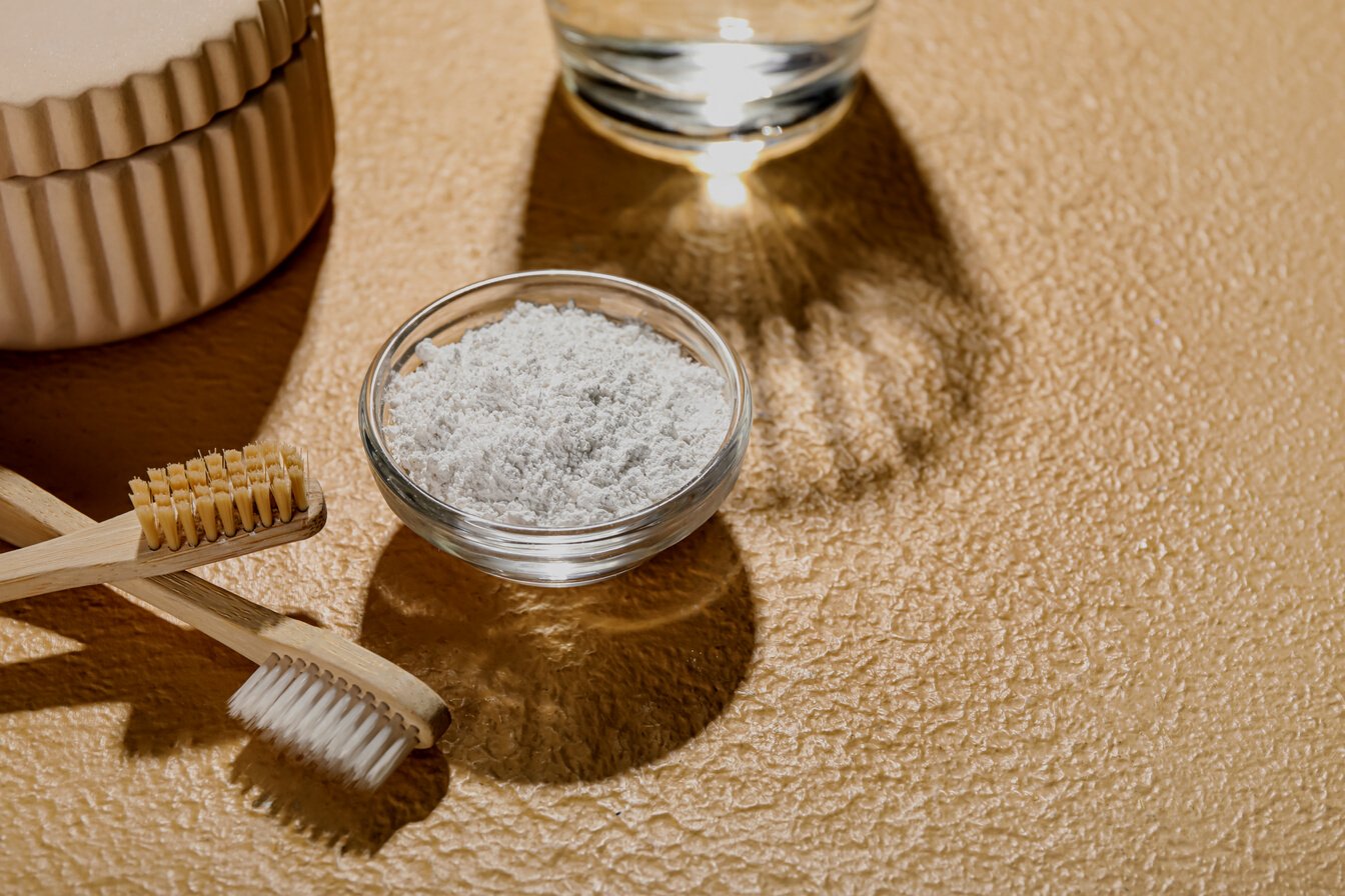 Bowl of Tooth Powder with Brushes on Beige Background, Closeup